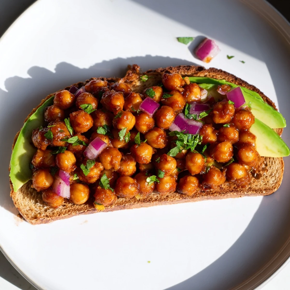 Close-up of hearty BBQ chickpeas on toast, a satisfying vegan lunch with visible texture and fresh toppings.