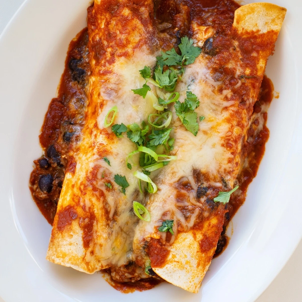 Baked Cheesy Bean Enchiladas with a golden, bubbly cheese topping, ready to serve with cilantro.