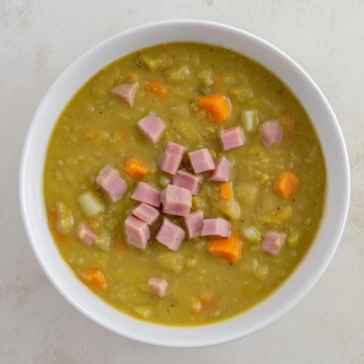 A close-up shot of rich Hearty Split Pea and Ham Soup with visible ham and vegetables simmering.