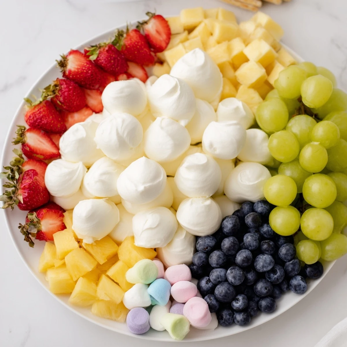 Cloud & Rainbow Grazing Board with colorful fruits, cheeses, and sweet candies arranged like a rainbow.