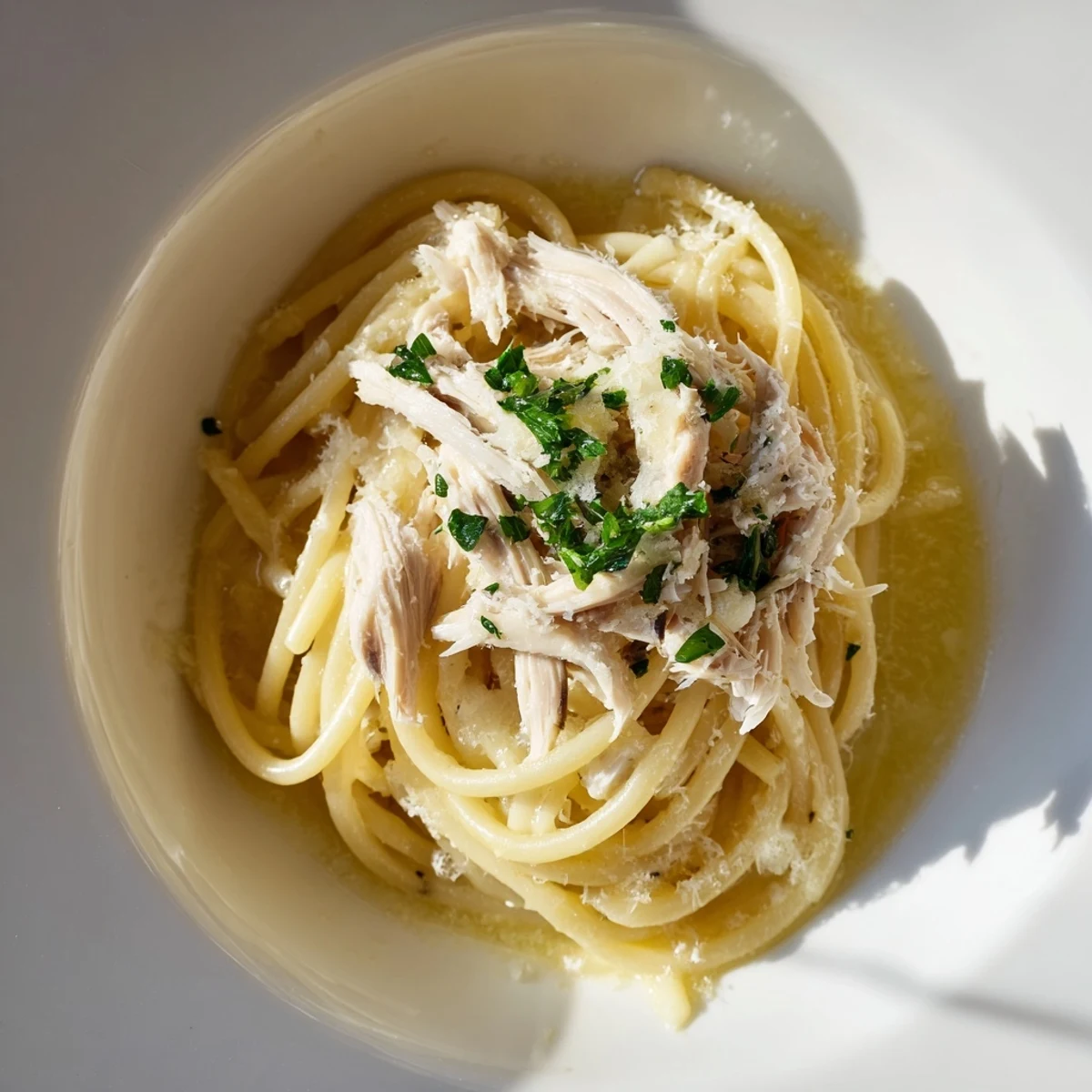 Fluffy shredded chicken tops a plate of Simple Garlic Butter Bucatini, ready to savor.