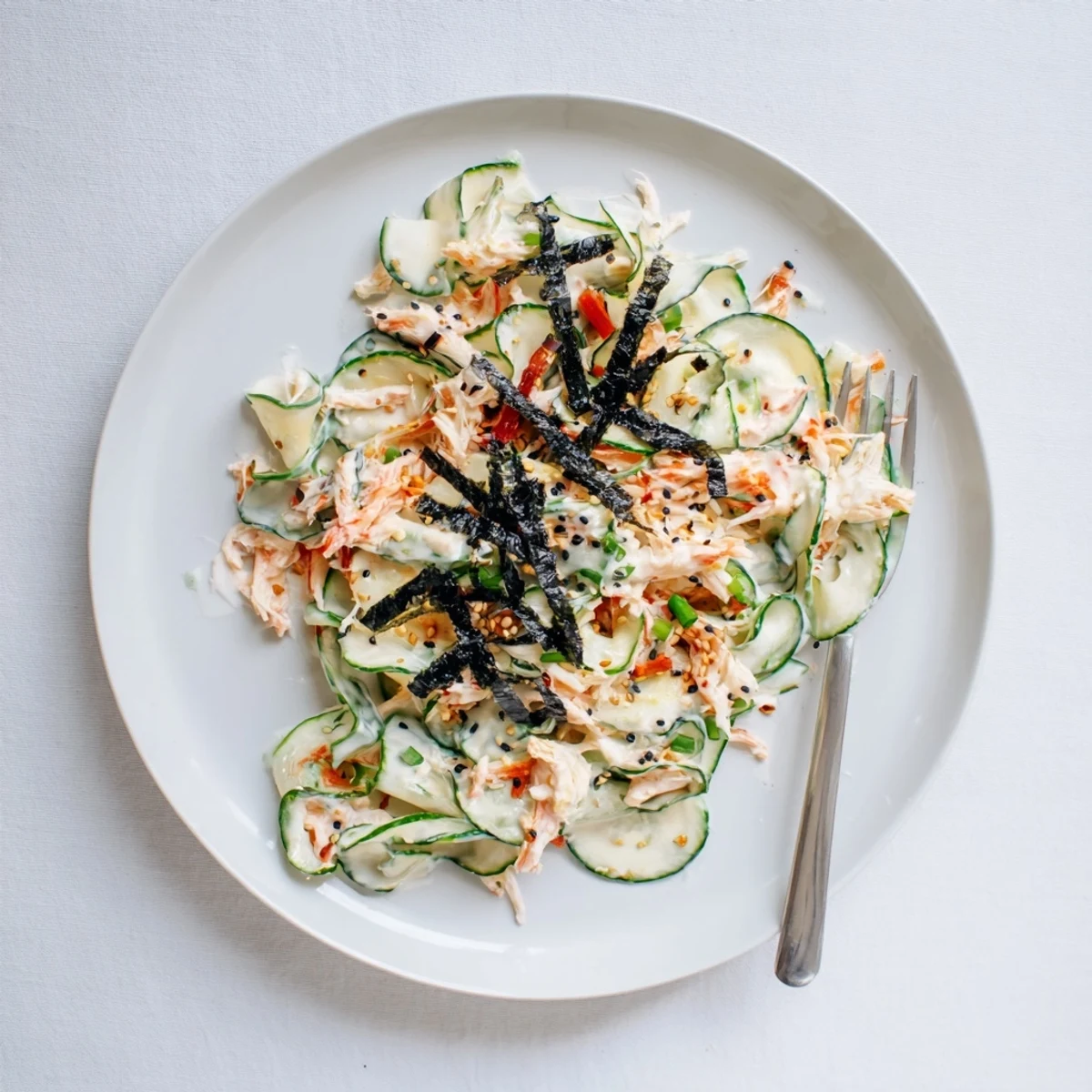 Light and creamy California Roll Cucumber Salad featuring tender imitation crab, crisp cucumbers, and toasted sesame seeds on a plate.