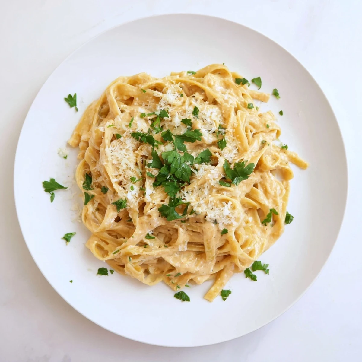 Hearty plate of Sriracha Honey Pasta with fettuccine tossed in a creamy, garlicky sauce, topped with parmesan and red pepper flakes.  