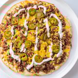 This photo features a hot Ground Beef Taco Pizza, ready to eat with toppings running over the crust.