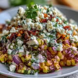 A vibrant Mexican Street Corn Salad featuring charred sweet corn, diced red bell pepper, and creamy dressing, garnished with Cotija cheese.