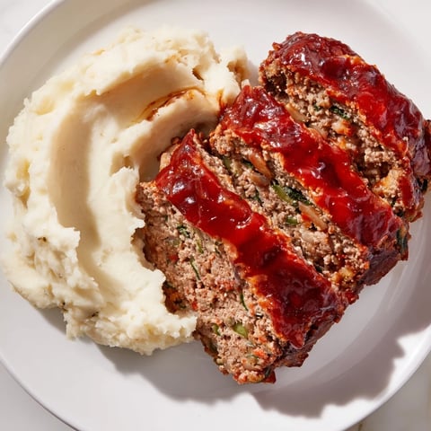 Juicy slices of Classic Meatloaf & Mashed Potatoes, steaming and ready to serve for dinner.