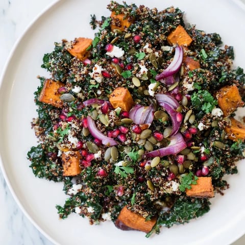 A colorful bowl of kale & quinoa salad, showcasing sweet potatoes and vibrant lemon dressing.