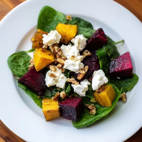 Golden-hued roasted beet, butternut, and spinach salad topped with creamy goat cheese, ready to eat.