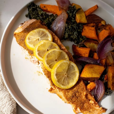 Flaky sheet-pan salmon with vibrant roasted vegetables and wilted greens, a hearty dinner.