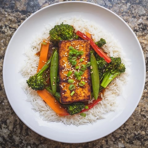 Golden, crispy pressed tofu steaks with colorful stir-fried vegetables and fluffy rice.