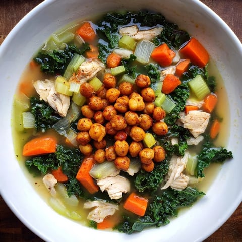 Steaming bowl of Chicken Kale Soup topped with golden, crispy chickpeas offering texture.