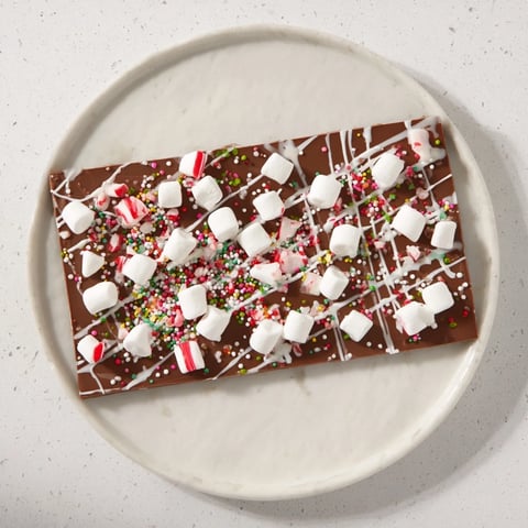 A visually enticing photo shows the festive, layered Viral Hot Chocolate Bomb Bark with marshmallows sprinkled on top.