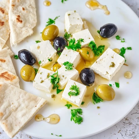 Turkish olives and cheese board, a colorful appetizer featuring feta, olives, honey, and warm pita.