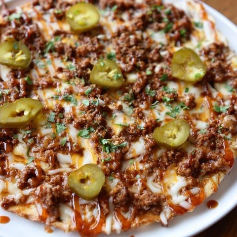 Golden, bubbly Spicy Ground Beef Pizza, ready to eat, with melted cheese and fresh herbs.