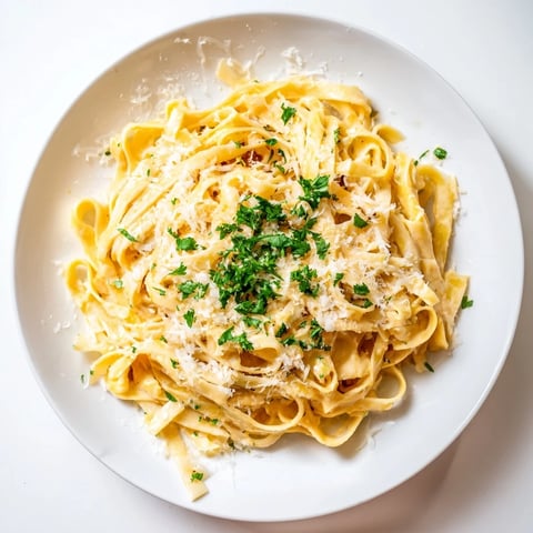 A close-up of creamy Sriracha Honey Pasta twirled on a fork, glistening with spicy-sweet sauce and fresh parsley garnish.  