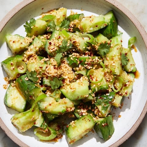 Zesty Chinese Spicy Smashed Cucumber Salad, a vegan delight, garnished with sesame seeds and fresh cilantro.