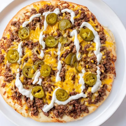 This photo features a hot Ground Beef Taco Pizza, ready to eat with toppings running over the crust.