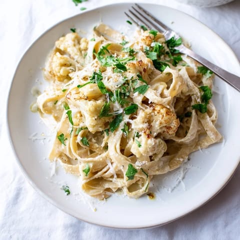 Creamy Roasted Cauliflower Alfredo clings to fettuccine, topped with fresh parsley and extra Parmesan for a comforting vegetarian dinner.