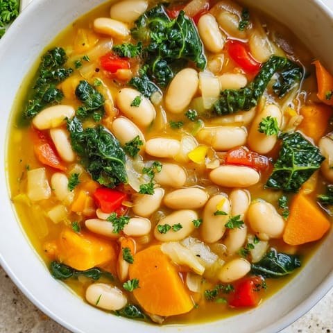 A savory bowl of Mediterranean White Bean Stew garnished with parsley and lemon wedges, served with crusty bread.