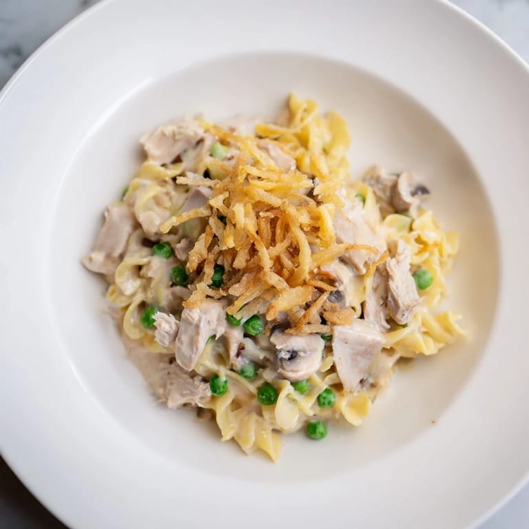 A close-up shot of creamy Homemade Tuna Noodle Casserole, bubbly and inviting with golden-brown fried onions.