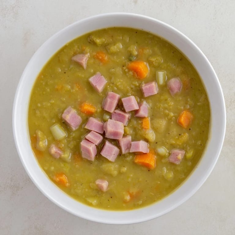 A close-up shot of rich Hearty Split Pea and Ham Soup with visible ham and vegetables simmering.