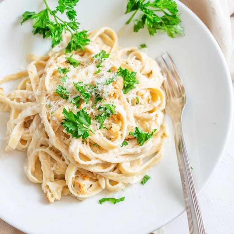 Savory roasted cauliflower Alfredo sauce coats pasta, with roasted garlic and nutmeg for a warm, cozy weeknight meal.