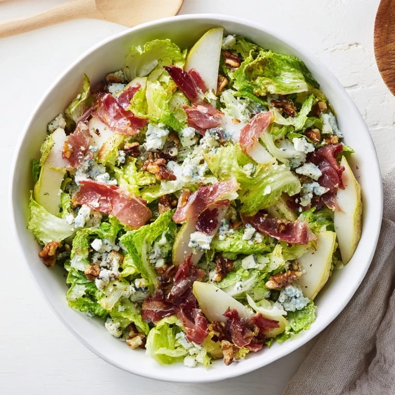 Frisée, Pear, Blue Cheese, and Crispy Prosciutto Salad drizzled with tangy vinaigrette, showcasing juicy pears and crumbled blue cheese.