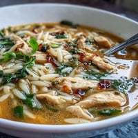 Bright lemon chicken orzo soup with tender chicken, fresh spinach, and a zesty citrus finish in a comforting bowl.